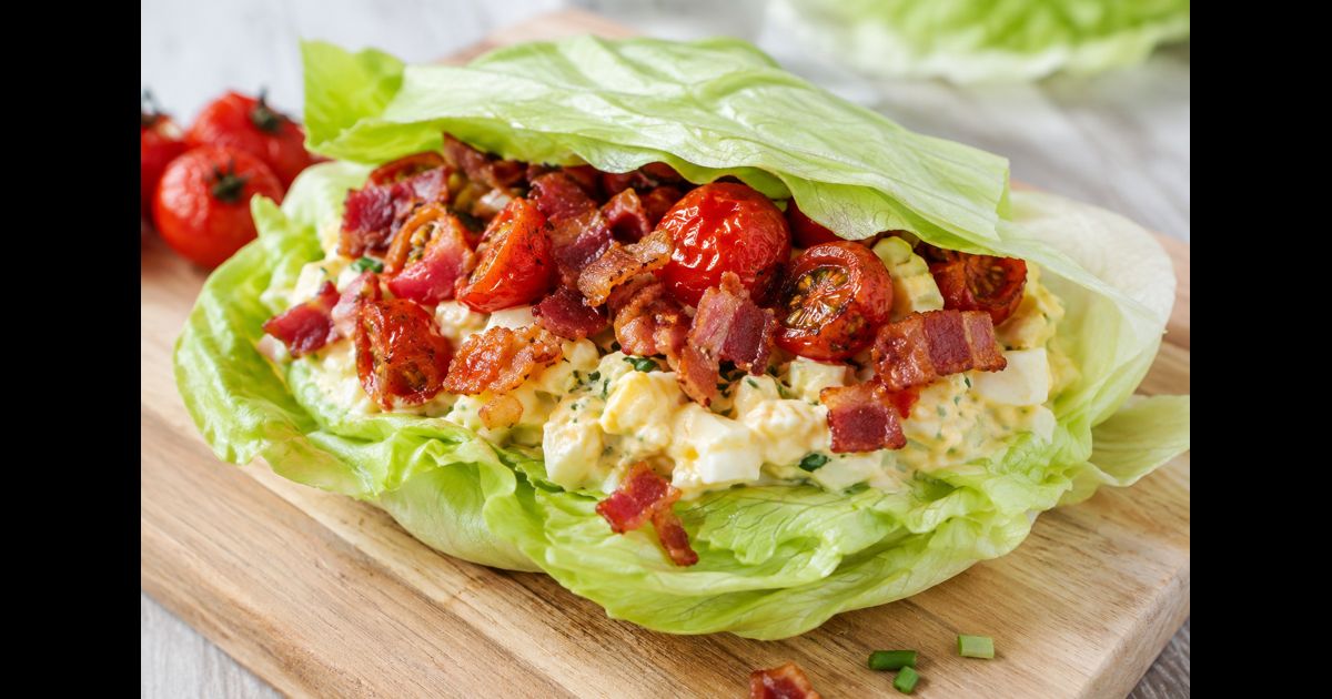 Sandwich sans pain à la salade aux œufs, bacon croustillant et tomates rôties dans une feuille de laitue iceberg